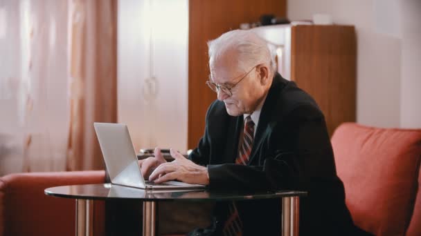 Grand-père âgé - le vieux grand-père tape sur un ordinateur puis pose ses lunettes sur la table avec désagrément — Video