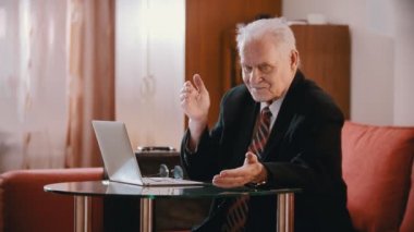 Elderly grandfather - old grandfather talking to a computer on a table in his room