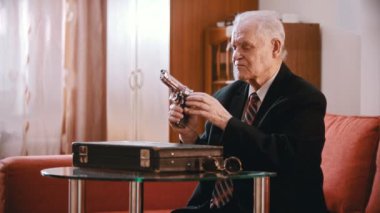 Elderly grandfather - old grandfather is taking out a reload gun and putting on glasses