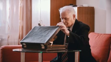Elderly grandfather - old grandfather is taking money from a suitcase and begining to count them