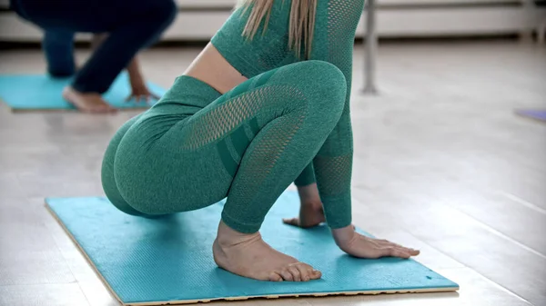 Mujeres jóvenes haciendo ejercicios de fitness en el luminoso estudio sobre esterillas de yoga — Foto de Stock