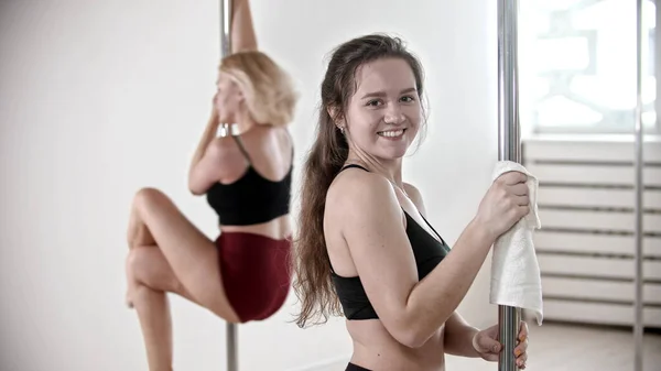 Due donne sorridenti che fanno un allenamento di pole dance nello studio bianco — Foto Stock