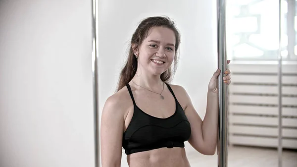 Jovencita sonriente parada junto al poste en el luminoso gimnasio —  Fotos de Stock