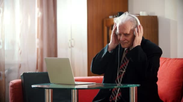 Grand-père âgé - grand-père âgé tient des écouteurs avec ses mains et oscille d'un côté à l'autre — Video