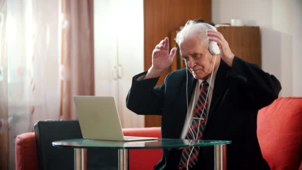 Elderly grandfather - grandfather is holding headphones with his hands and enjoying music — Αρχείο Βίντεο