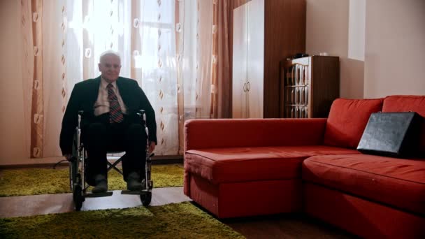 Пожилой дедушка - счастливый дедушка катается на инвалидной коляске по комнате — стоковое видео