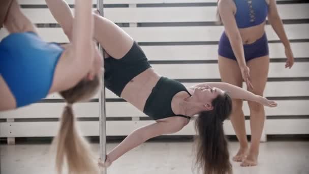 Женщины на занятиях по танцам на шесте в яркой фитнес-студии — стоковое видео
