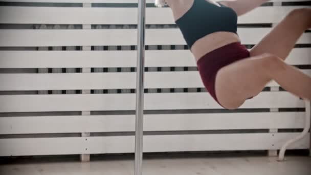 A blonde woman performing a pole dancing trick in the studio — Stock Video