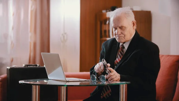 Elderly grandfather - old grandfather reloading weapon in his room — Stockfoto