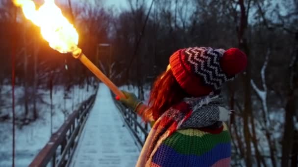 Una joven caminando sobre el puente sosteniendo una antorcha — Vídeos de Stock