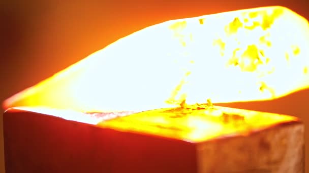 A kovács kalapáccsal üti a forró fémdarabot - kis darabok jönnek le a fémről — Stock videók