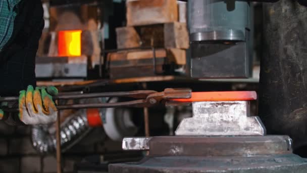 Blacksmith putting a longer piece of metal under the pressure of industrial forging machine — Αρχείο Βίντεο