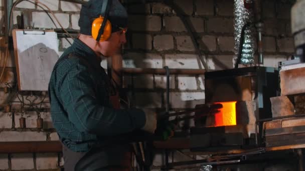 A man blacksmith heating up the hot detail in the furnace — Αρχείο Βίντεο