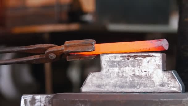 Smed som lägger en längre bit av glödande metall under trycket av smidesmaskin — Stockvideo
