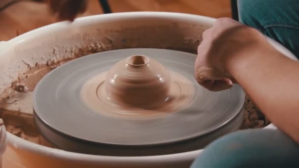 Pottery - the master is pouring water into the hole in the clay and continuing to spin it — Stock Video