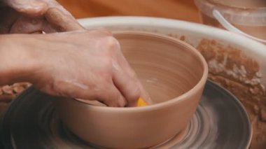 Çanak çömlek - usta tabağın altını sarı bir süngerle siliyor.