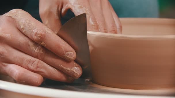 Keramik - mästaren hjälper till med en speciell metallspatel för att jämna ut ytan av lerskålen — Stockvideo