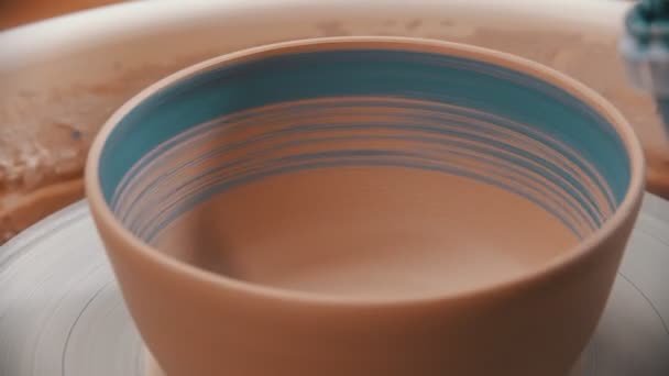 Cerâmica - o homem está pintando uma tigela de barro dentro com escova azul em uma roda de cerâmica — Vídeo de Stock
