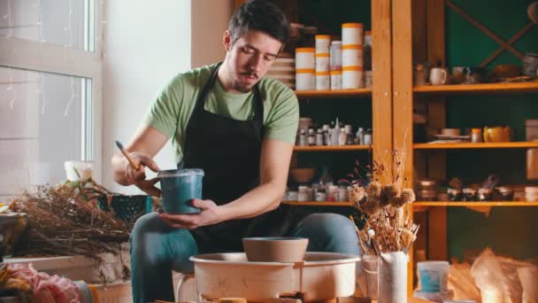 Pottery - the master is putting down a bucket of paint and wiping sweat from his forehead — Stock Video