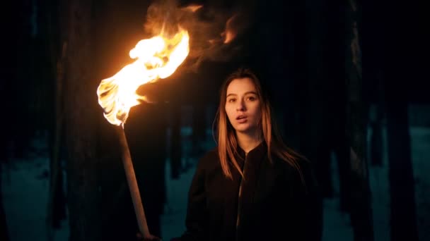Молодая женщина с факелом позирует в ночном лесу — стоковое видео