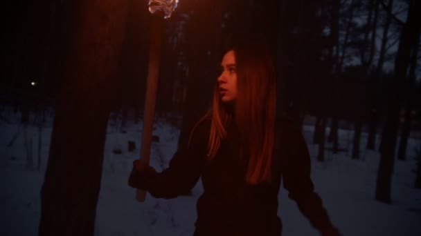 Young woman with torch trying to run away from the danger and looking around in the forest — Αρχείο Βίντεο