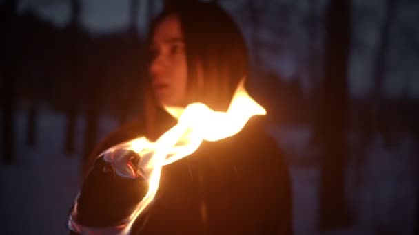 Jeune femme debout dehors la nuit avec une torche de feu et regardant autour — Video
