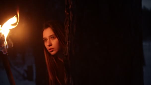 Jeune femme effrayée avec torche regardant de l'arbre des deux côtés 