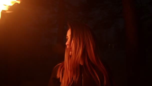 Karanlık ormanda elinde meşale tutan genç bir kadın. — Stok video