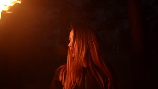 Mujer joven sosteniendo antorcha de fuego de pie en el bosque oscuro — Vídeos de Stock