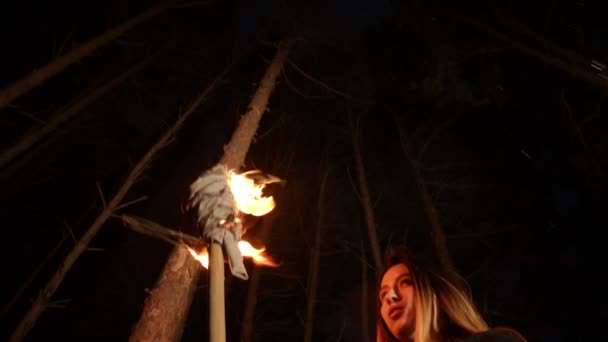 Young lost woman standing in winter forest at night with a handmade torch — Stock Video
