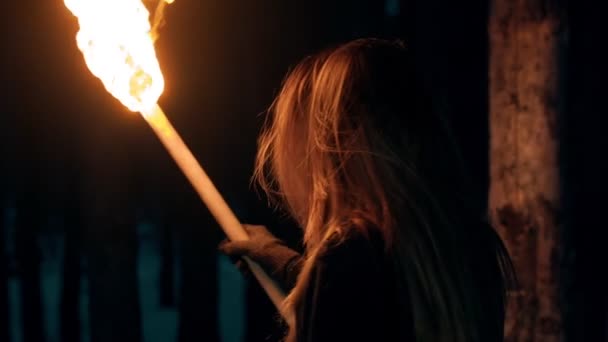 Молодая женщина, стоящая в ночном лесу с факелом - уходя в лес — стоковое видео