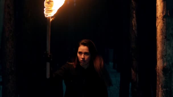 Jeune jolie voyageuse marchant dans les bois la nuit tenant une torche 