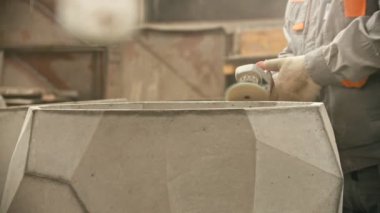 Concrete industry - worker in protective suit polishing a big concrete figure with a grinder