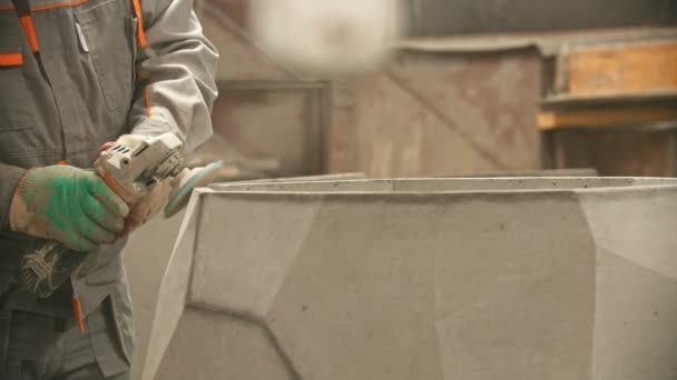 Industria del hormigón - trabajador en traje protector puliendo un artículo de hormigón grande con una amoladora — Vídeo de stock