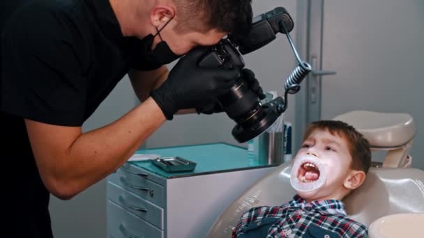 Un niño pequeño que está recibiendo un tratamiento en la odontología - tomando fotos de la cavidad oral de los niños — Vídeo de stock
