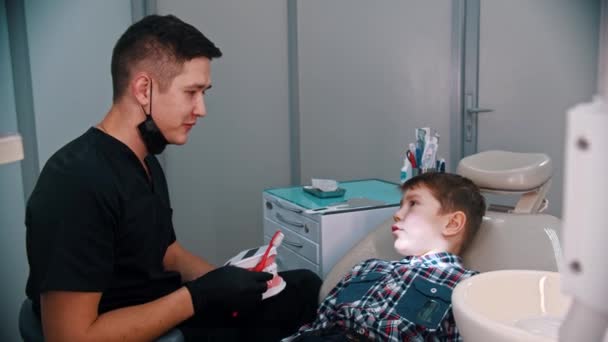 Un niño pequeño que tiene un tratamiento en la odontología moderna - hablando de la higiene — Vídeo de stock