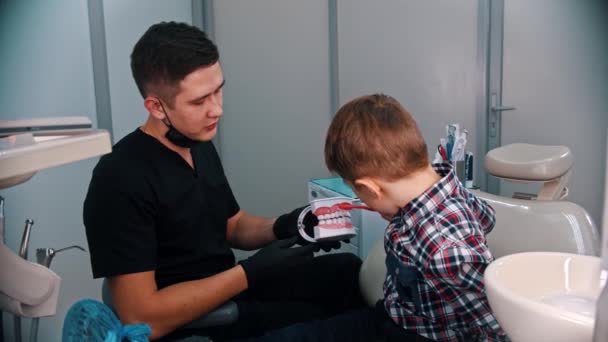 Ein kleiner Junge bei einer Behandlung in der Zahnmedizin - erklärt, wie man Zähne am Kiefermodell putzt — Stockvideo