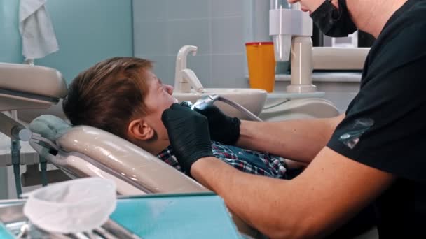 Een kleine jongen die zijn tanden laat doen in de moderne tandheelkunde — Stockvideo