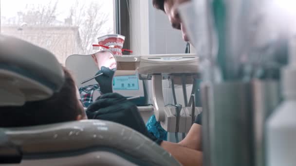 Een tandarts onderzoekt de mond van een jonge jongen — Stockvideo