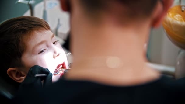 Um dentista examina a boca de um menino na odontologia moderna — Vídeo de Stock