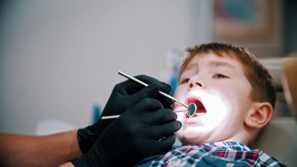 Un niño estresante con dientes de bebé que tiene un tratamiento en la odontología — Vídeo de stock