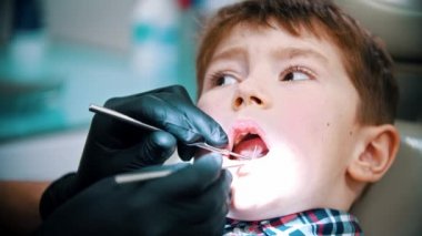 Bebek dişli küçük bir çocuk modern dişçilikte tedavi görüyor. Ağız boşluğunu muayene ediyor.