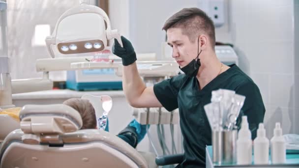 Joven dentista preparando todo para el control de la boca de un niño pequeño — Vídeo de stock