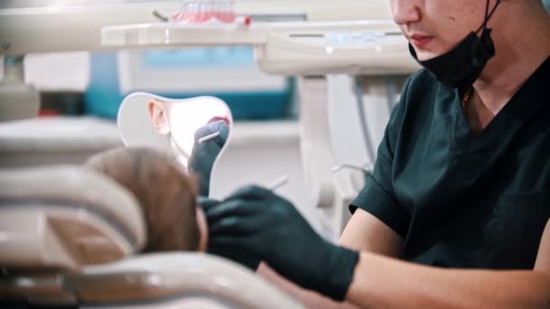 Jovem dentista verificando a boca de um menino — Vídeo de Stock