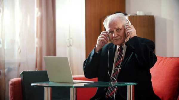 Ein alter Mann hält Kopfhörer in den Händen und hört Musik — Stockfoto