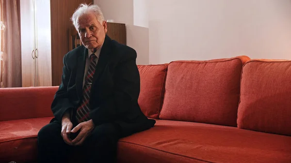 Elderly grandfather - sad old grandfather is sitting on a sofa — Stockfoto