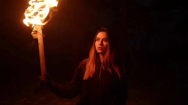 Jovem morena viajante andando na floresta à noite segurando uma tocha — Fotografia de Stock