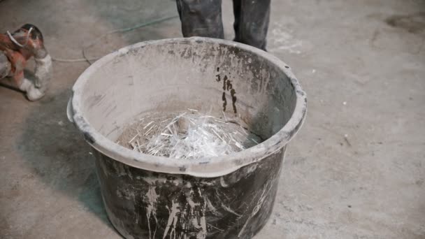 Betonindustrie - werknemer in handschoenen op het punt om het beton te mengen - toevoegen van stukjes glas in de mix — Stockvideo
