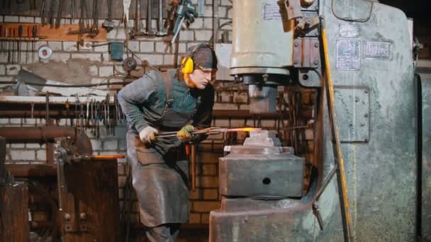 Forgeage industrie - un forgeron homme mettre le morceau chaud de métal sous la pression de la grande machine — Video