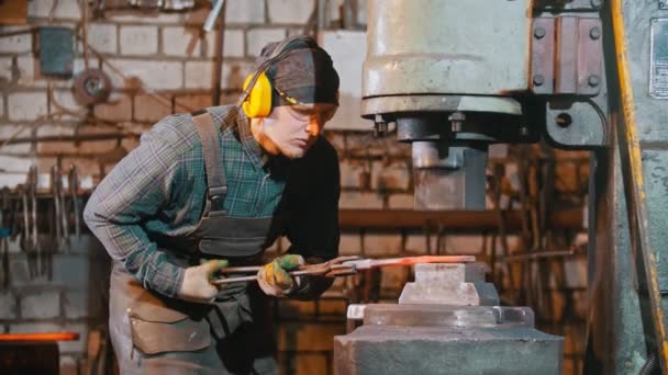 Przemysł kuźniczy - człowiek kowal stawiający gorący kawałek metalu pod presją wielkiej maszyny - robiący nóż — Wideo stockowe